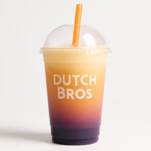 Modern frosted Dutch Bros cup with domed lid showing layered purple, peach, coconut, and orange Rocky Point drink on a white background.

